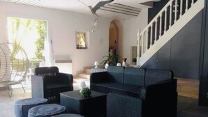A modern living room with a sofa set, round ottomans, and a television. - Magnificent residence with heated indoor pool (Guipry-Messac)