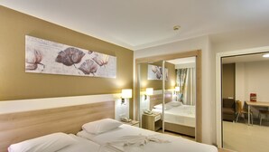 A hotel room with a large bed, a bedside table with a lamp, a mirror, and a wall-mounted artwork. - Novella Apart Hotel (Alanya)