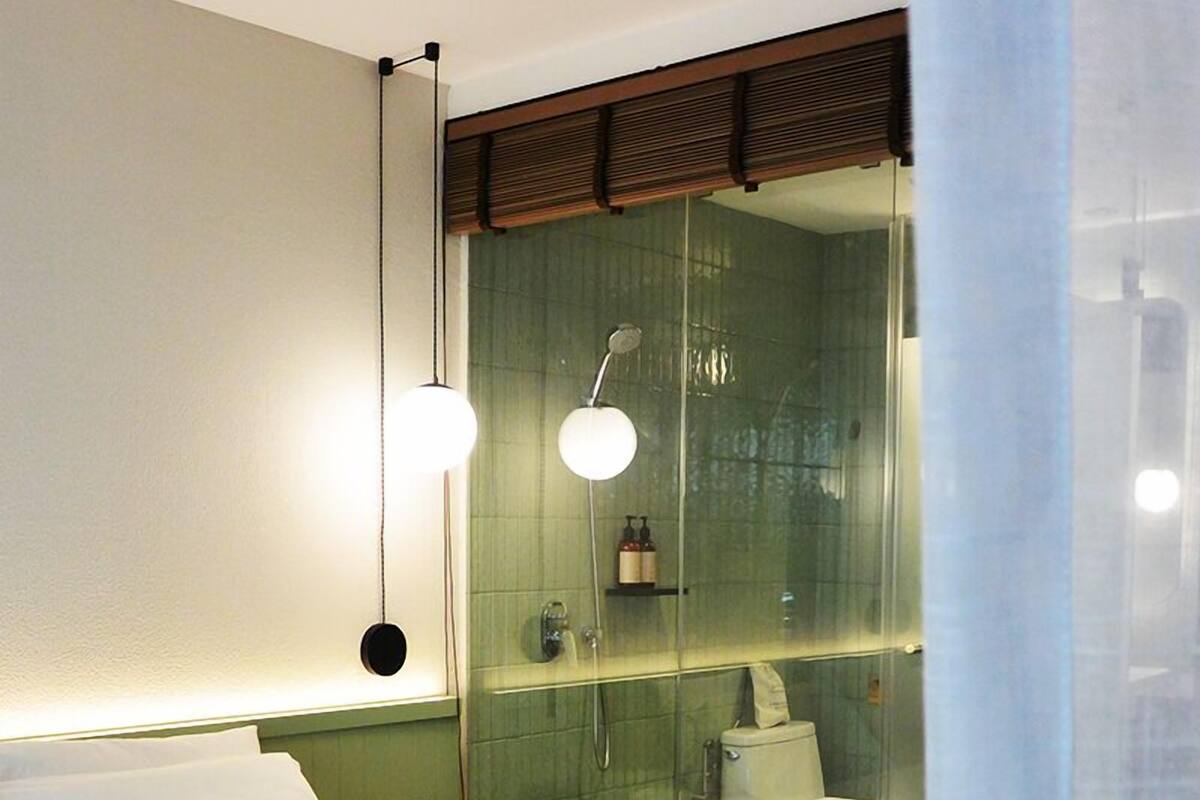 A modern bedroom with a large bed, a glass shower enclosure, and a ceiling fan.