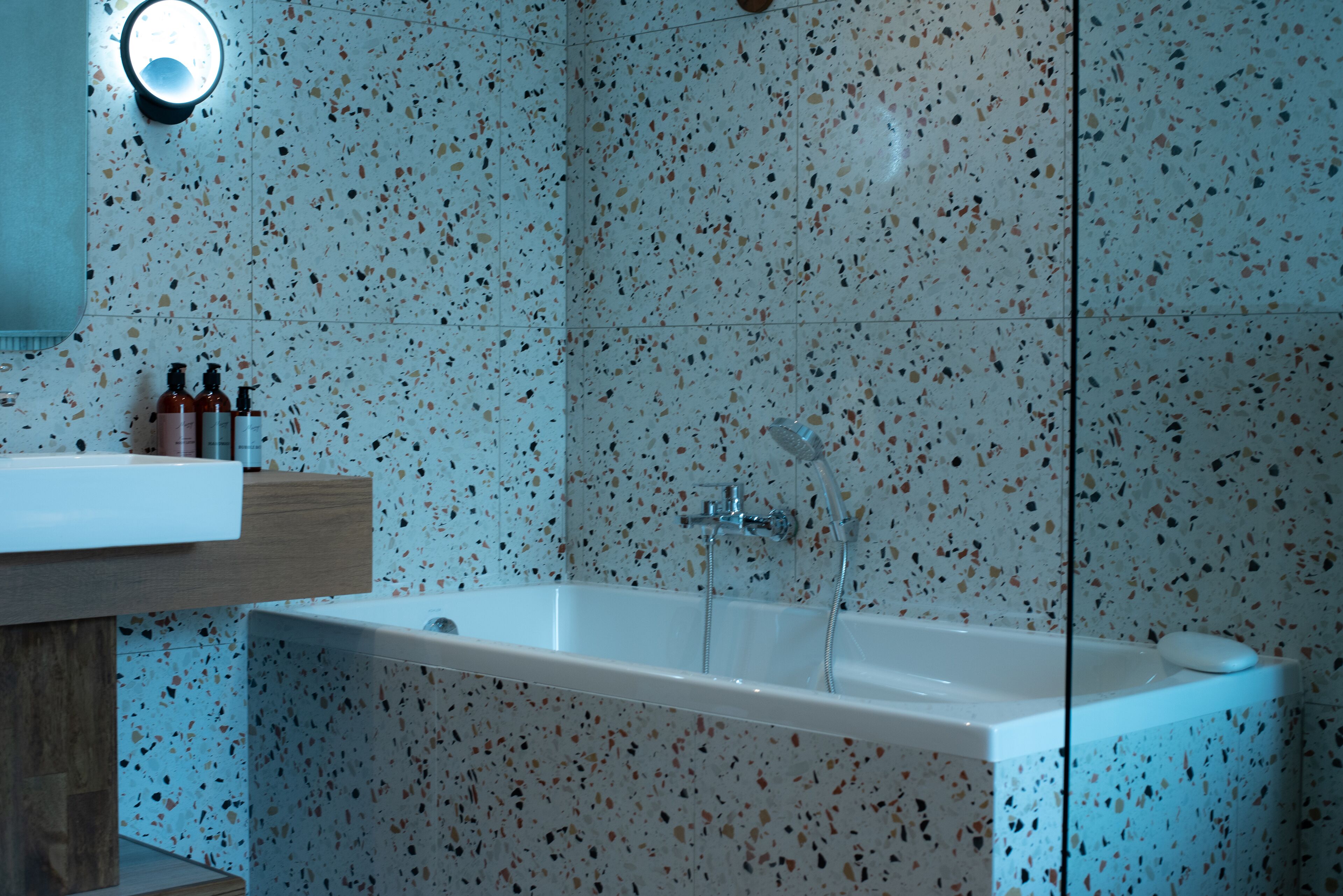 A modern bathroom with a freestanding bathtub, a wooden vanity, and a wall-mounted mirror.