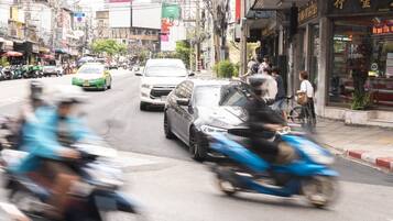 A busy street with motorcycles and cars, shops, and a sign indicating 'Thong Lo'.