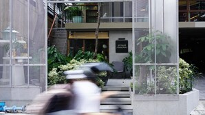 A modern building entrance with a metal mesh fence, a staircase leading to a second floor, and a sign with Thai script. - Karaarom Hotel (Bangkok)