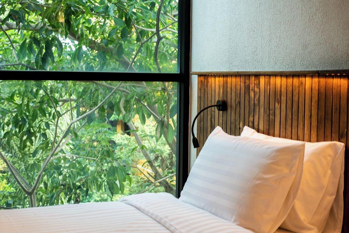 A bedroom with a large window, a wooden headboard, and a bed with white bedding.