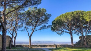A pathway leading through a grassy area with trees and stone walls, with a clear view of distant hills. - Amazing home in Castiglion Fiorentino (Castiglion Fiorentino)
