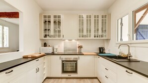 Una cocina moderna con armarios blancos, horno integrado, encimera negra y una ventana que proporciona luz natural.