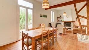 Un comedor amplio con una mesa y sillas de madera, una lámpara colgante y una chimenea de piedra.