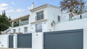 Et moderne hus med to etager, en balkon, store garageporte og en trappe op til øverste etage.