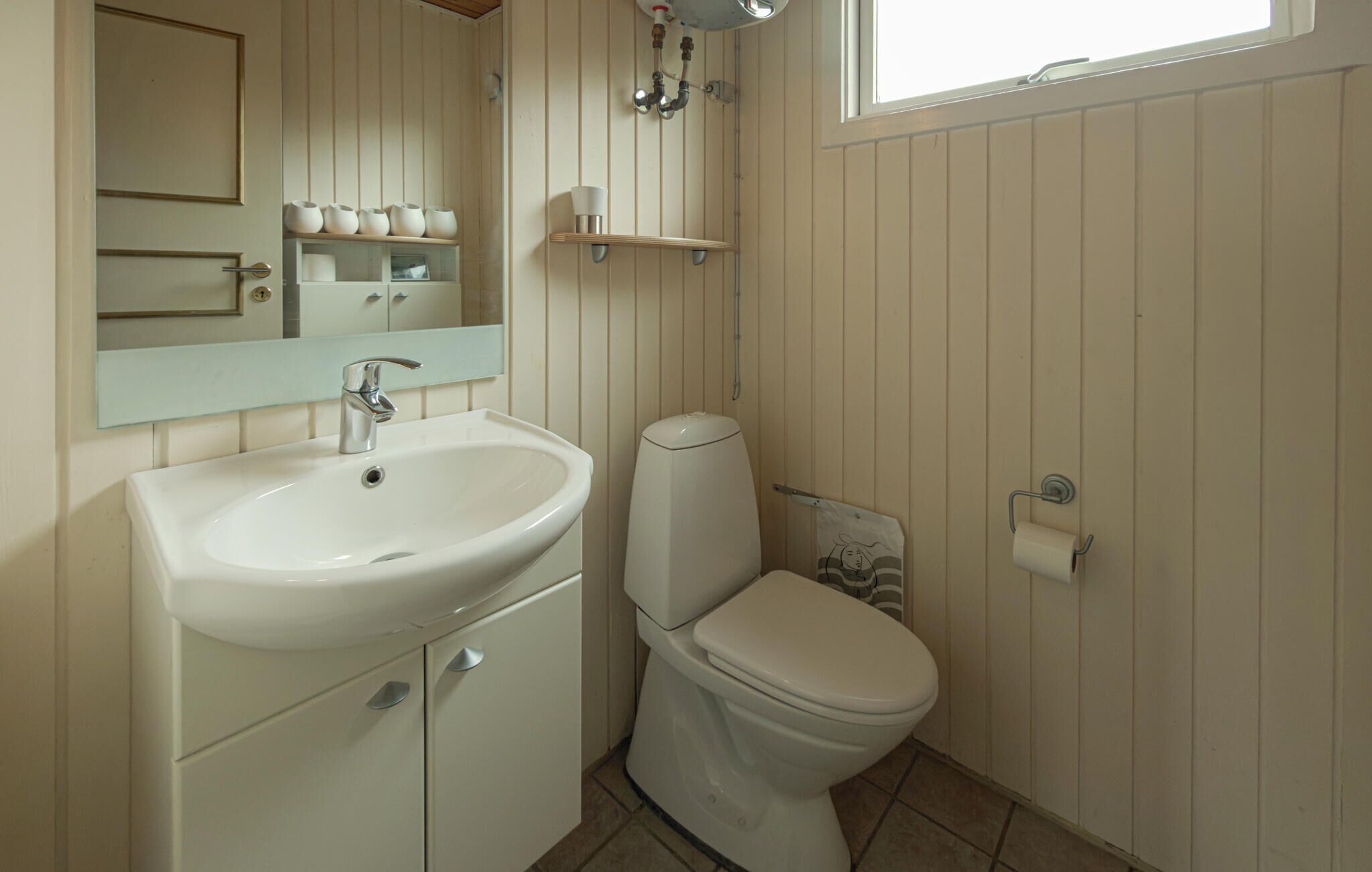 Ein Badezimmer mit Waschbecken, Toilette, Spiegel und Fenster.