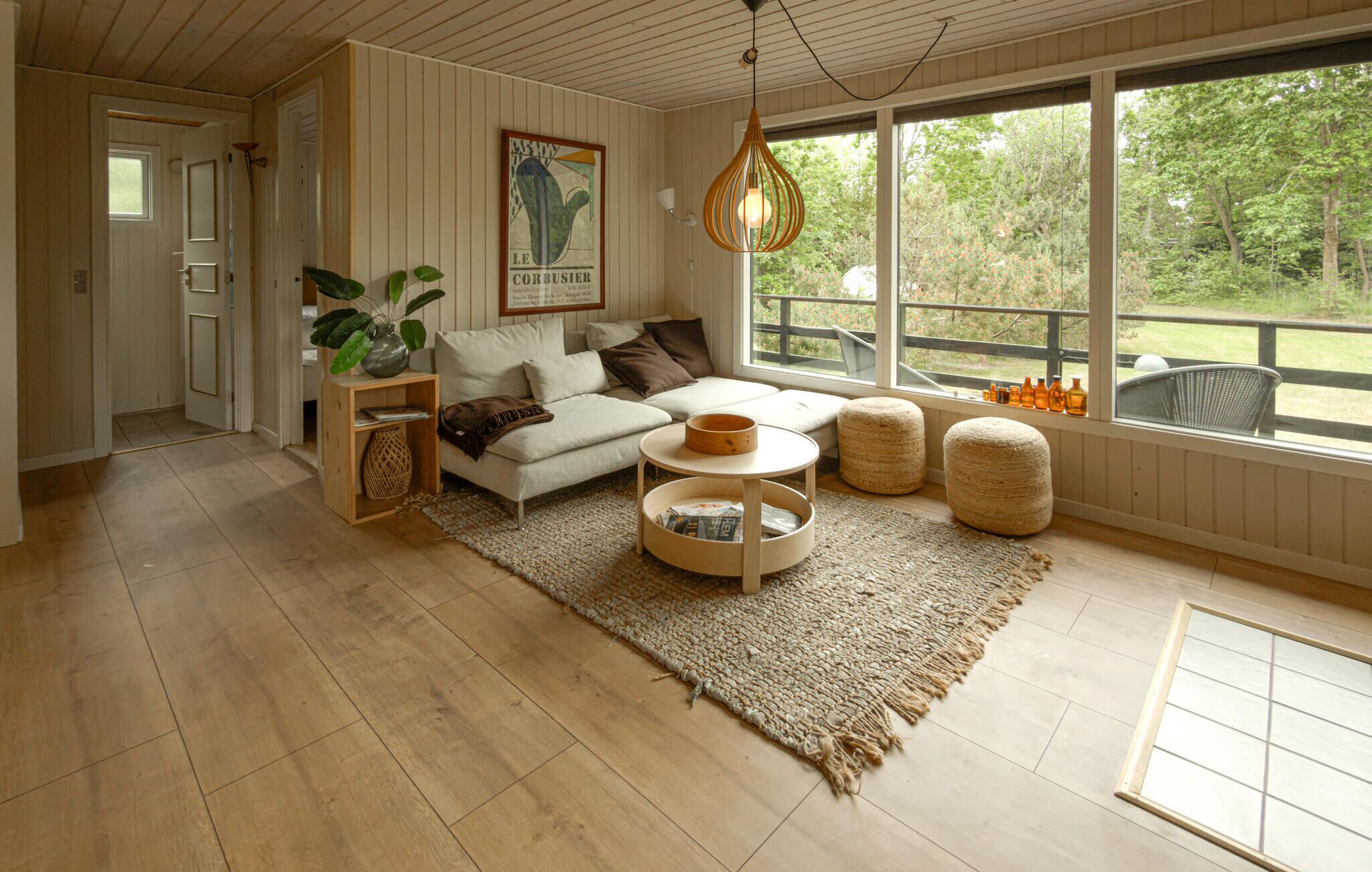 Ein Wohnzimmer mit Sofa, Hocker, Couchtisch und einer Pendelleuchte.