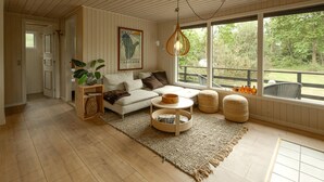 Una sala de estar con sofá, reposapiés, mesa de centro y lámpara colgante.