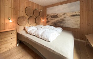 Un dormitorio de madera con cama, lámparas fijadas a la pared y un cuadro grande.