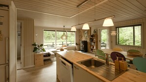 Una cocina moderna con armarios de madera, una isla central con fregadero y un comedor con sillas.