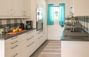 Compact kitchen with a sink, coffee maker, kettle, and cutting board.