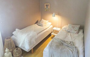 Two single beds with white duvets and matching pillows, a nightstand, and a decorative item.