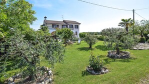 A house with a well-maintained lawn, several trees, and a clear sky. - 2 bedroom cozy apartment in Grado (Grado)