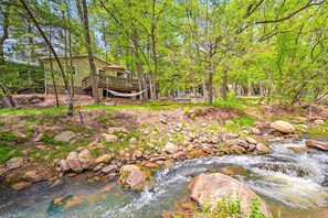 Escape to a peaceful riverside retreat with a cabin surrounded by lush greenery and a serene stream.