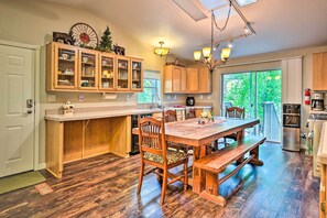 Enjoy meals in the kitchen with a central island, sink, and ample counter space, adjacent to a dining area with a wooden table and chairs.