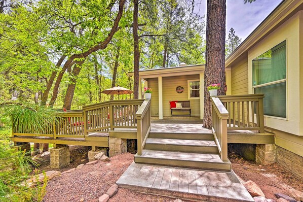 Step up to a serene retreat with a porch surrounded by lush greenery and trees.