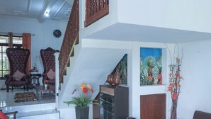 Amplia sala de estar con una escalera, un sofá, una mesa de centro y plantas decorativas.