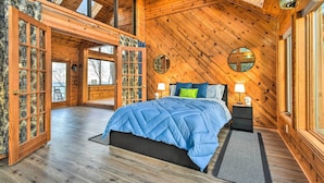 A spacious bedroom with a large bed, wooden walls, and a skylight. - Lakefront Applegate Retreat w/ Private Beach! (Applegate)