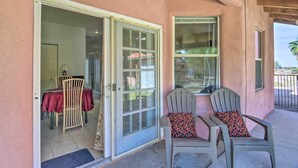 A covered patio area with two Adirondack chairs and a sliding glass door leading to an indoor dining space. - 'Best Night's Sleep' Apt Near Skydive Arizona (Eloy)