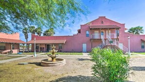 A pink building with a central courtyard, a fountain, and a staircase leading to an upper level. - 'Best Night's Sleep' Apt Near Skydive Arizona (Eloy)