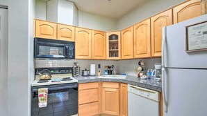 A kitchen with wooden cabinets, a microwave, stove, and a refrigerator. - 'Best Night's Sleep' Apt Near Skydive Arizona (Eloy)