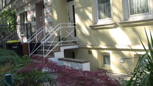 A multi-story building with a white exterior, a visible number '5' on the facade, and a metal staircase leading to the entrance.