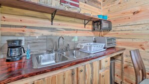 A kitchen with wooden walls, a double sink, a coffee maker, a microwave, and a toaster. - Updated Studio Cabin in Ozark w/ Yard & Mtn View (Ozark)
