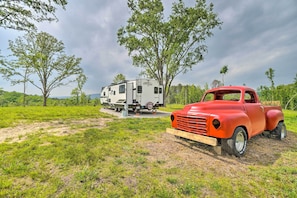 Park your vehicle in a grassy field surrounded by trees and open space.