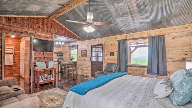 A wooden cabin interior with a bed, a desk, and a dining area. - Updated Studio Cabin in Ozark w/ Yard & Mtn View (Ozark)