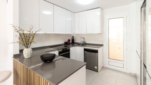 Een moderne keuken met witte kasten, een centraal eiland en een inbouw vaatwasser.