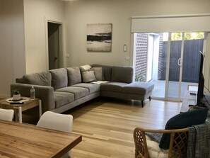 Relax in this stylish living room with a large L-shaped sofa, coffee table, and wicker chair.