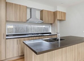 Modern kitchen with stainless steel range hood, double sink, and wooden cabinetry.