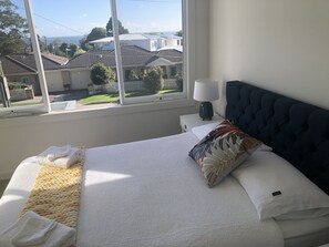 Enjoy a peaceful retreat with a view of the surrounding houses and clear sky from this cozy room featuring a comfortable bed and stylish decor.