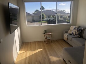 Enjoy a view of the surrounding neighborhood from the large window in this room, featuring a sofa, small table, and chair.