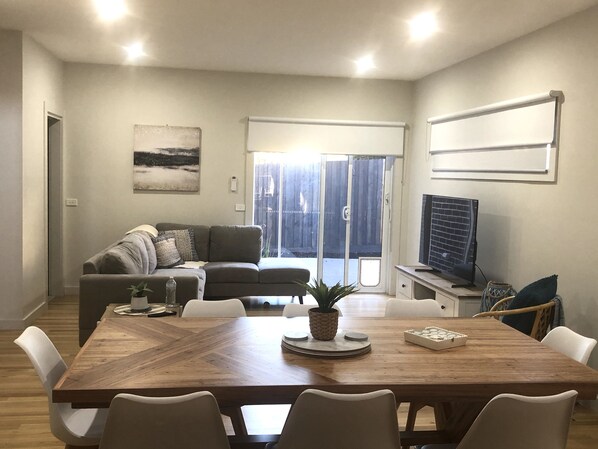 Relax in this stylish living space with a central dining table, comfortable sofa, and large window offering a view of the outdoors.