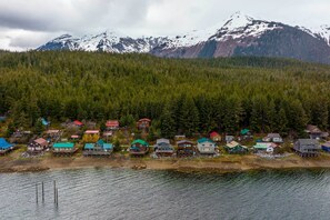 A lakeside village with houses on stilts, surrounded by dense forest and snow-capped mountains. - Remote Island Escape w/ Breathtaking Views (Tenakee Springs)