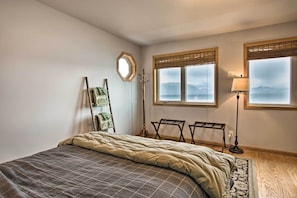 A bedroom with a bed, a standing lamp, a window with a view, and a coat rack. - Remote Island Escape w/ Breathtaking Views (Tenakee Springs)