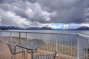 A deck with a table and chairs overlooking a lake with mountains in the background.