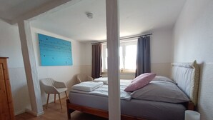 Ein Schlafzimmer mit einem Bett, einem Sessel, einem Holzschrank und einer blauen Wand mit einer Vogelillustration.