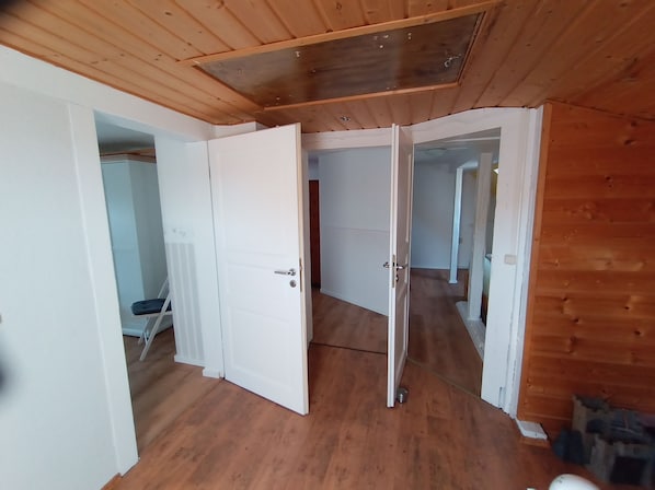 A room with wooden flooring, white walls, and a sloped ceiling.
