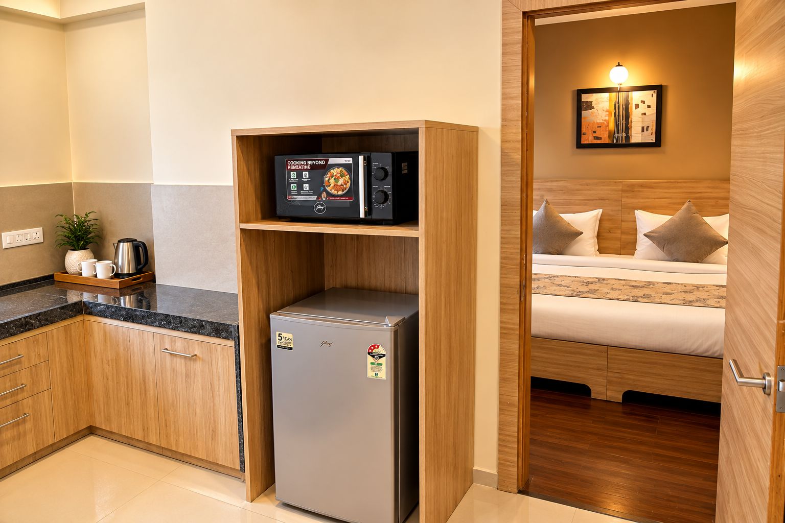 Una kitchenette compacta con microondas integrado, un refrigerador pequeño y una cafetera.