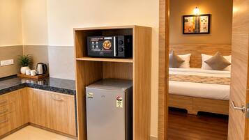 Una kitchenette compacta con microondas integrado, un refrigerador pequeño y una cafetera.