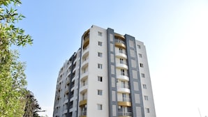 A high-rise residential building with multiple balconies, large windows, and a modern architectural design. - STARLIT SUITES SHIRDI (Rahata)