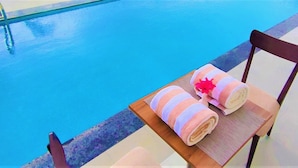 A poolside area with a chair and a towel rack. - STARLIT SUITES SHIRDI (Rahata)