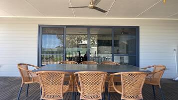 An outdoor patio with a table and chairs, a ceiling fan, and a view through a glass door.