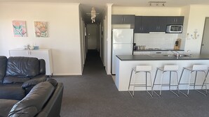 Eine moderne Küche mit Kühlschrank, Mikrowelle und Barhocker.