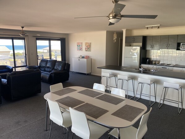 Relax in a spacious living area with a comfortable sofa and dining table for four, surrounded by chairs. Enjoy a city view from large windows.