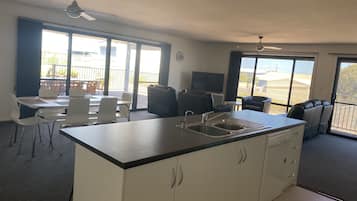 A compact kitchen with a central island, a dining area with chairs, and a seating area with a sofa and chairs.